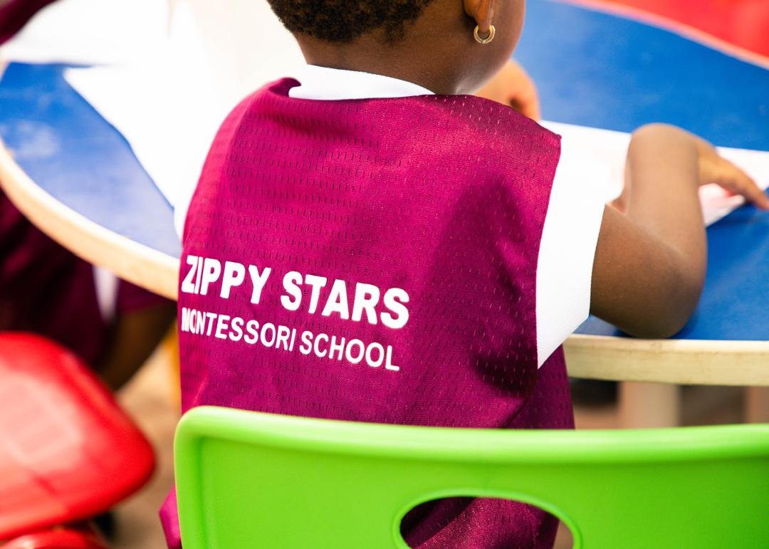 A pupil in a Zippy Stars Montessori School vest working at a table