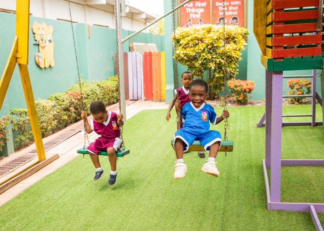Children playing joyfully on the swings at Zippy Stars Montessori School