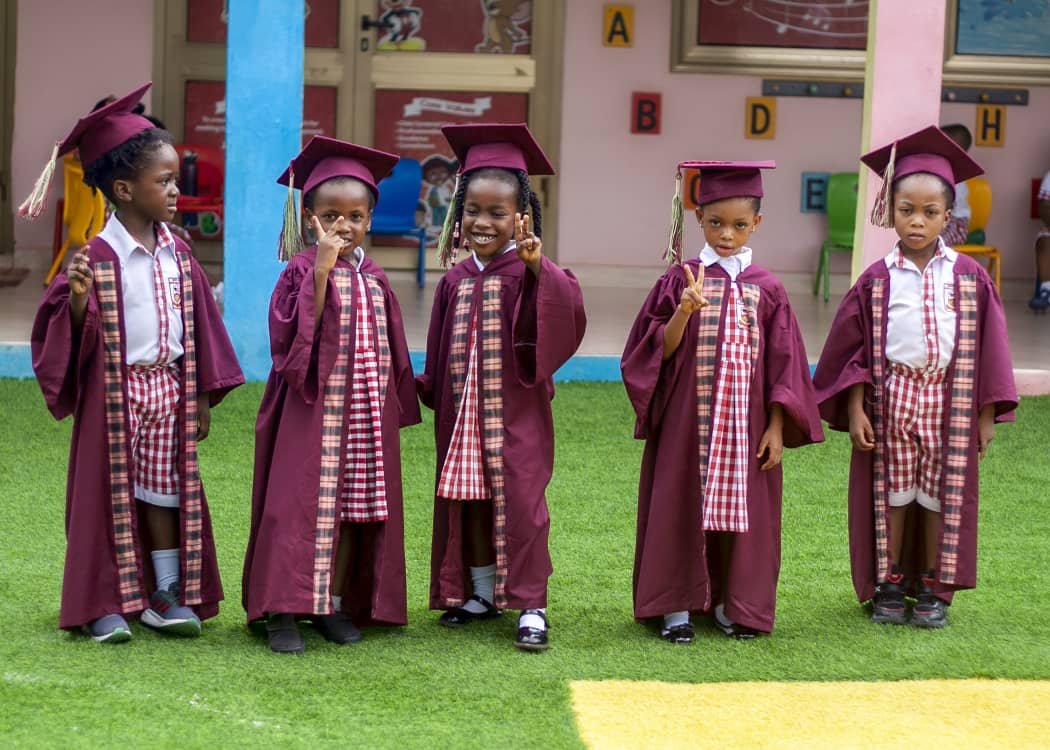 Graduating pupils in maroon caps and gowns posing together